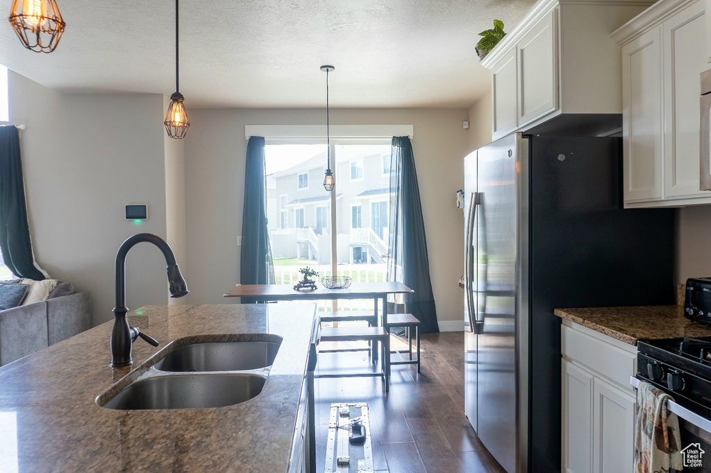 Kitchen with dark wood-style floors, white cabinets, decorative light fixtures, and a textured ceiling
