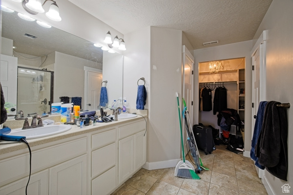 Bathroom with a sink, visible vents, a spacious closet, a shower stall, and double vanity