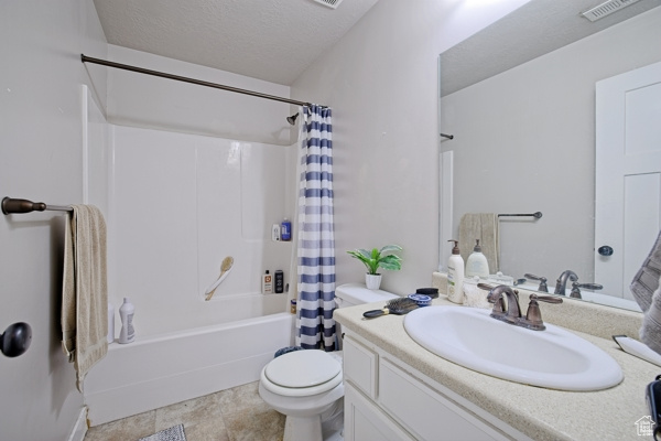 Full bath featuring toilet, a textured ceiling, visible vents, shower / bathtub combination with curtain, and vanity