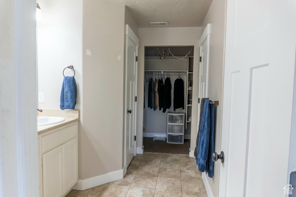 Bathroom featuring vanity, a textured ceiling, and a spacious closet