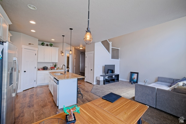 Kitchen with a sink, stainless steel appliances, recessed lighting, open floor plan, and white cabinets