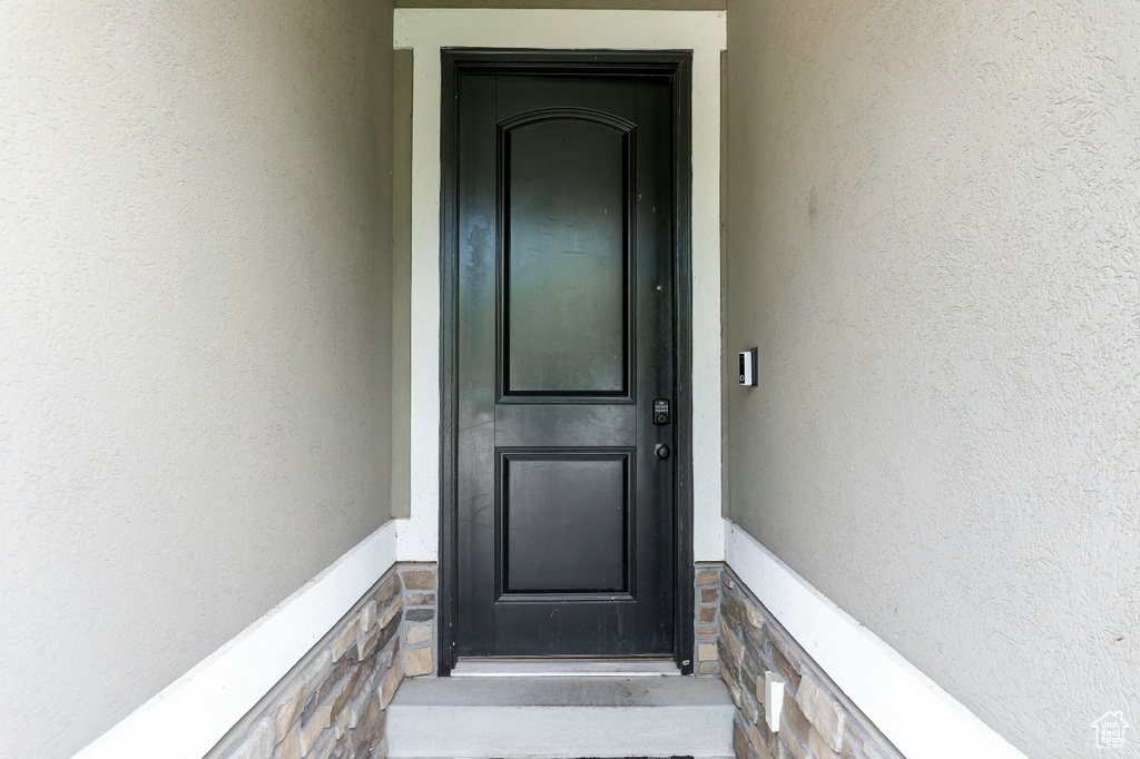 Doorway to property featuring stucco siding and stone siding