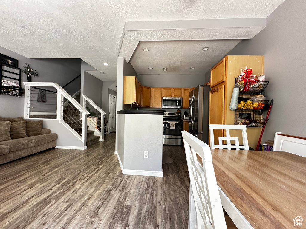 Dining area with wood finished floors, stairs, a textured ceiling, baseboards, and recessed lighting