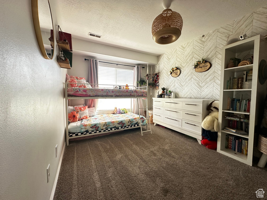 Bedroom featuring a textured ceiling, visible vents, baseboards, and dark carpet