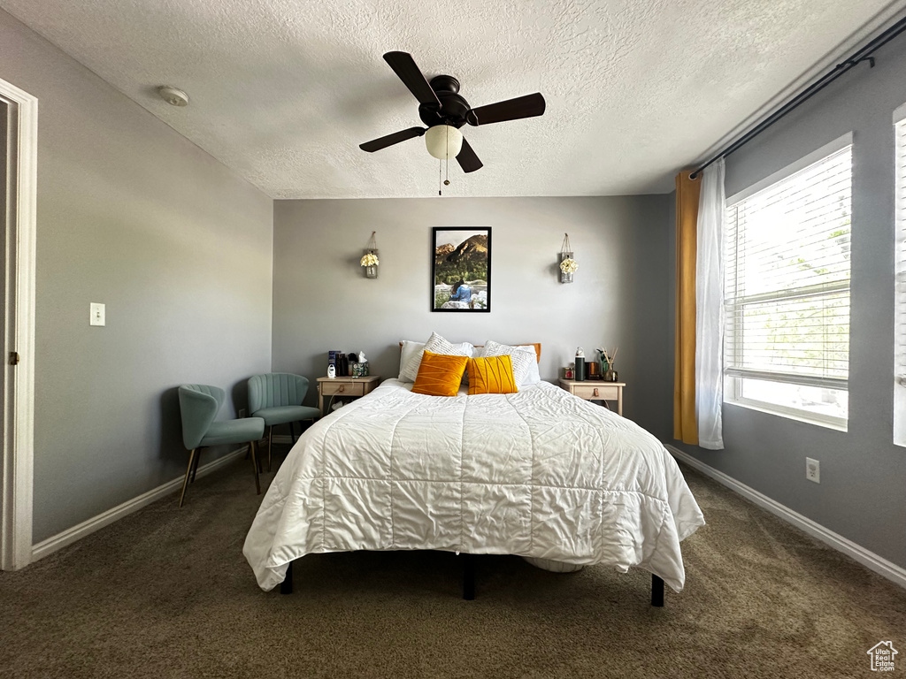 Bedroom featuring carpet flooring, a textured ceiling, baseboards, and a ceiling fan