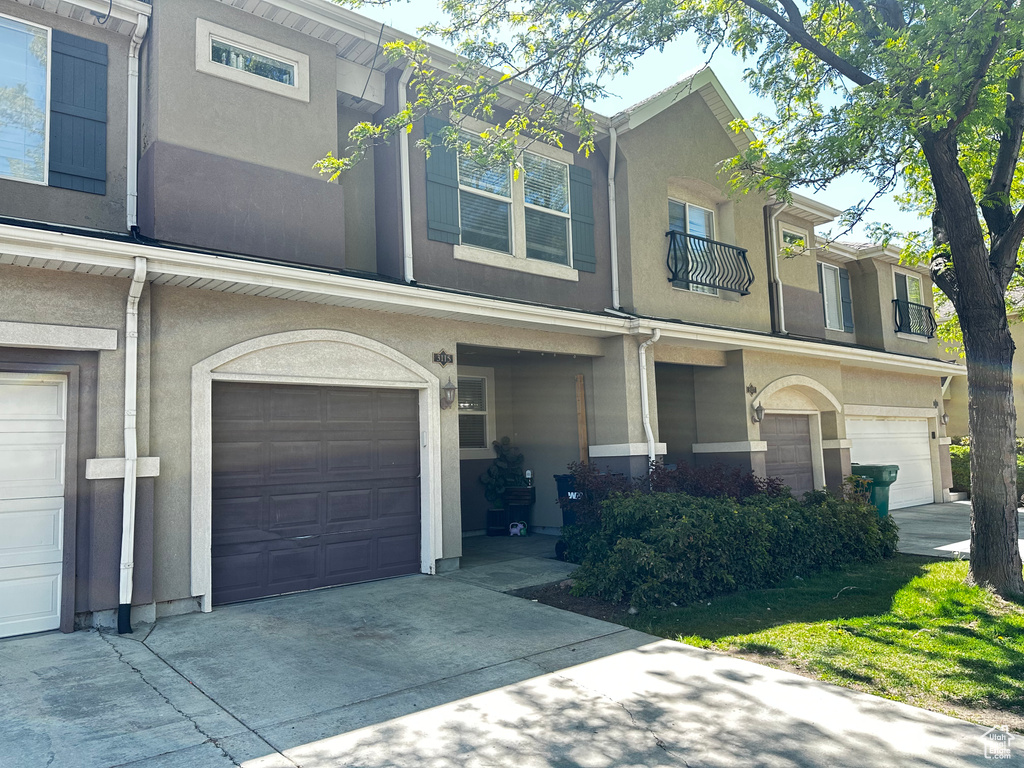 View of property featuring stucco siding, driveway, and a garage