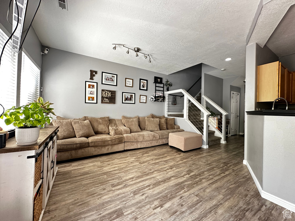 Living area featuring a textured ceiling, stairway, wood finished floors, and baseboards