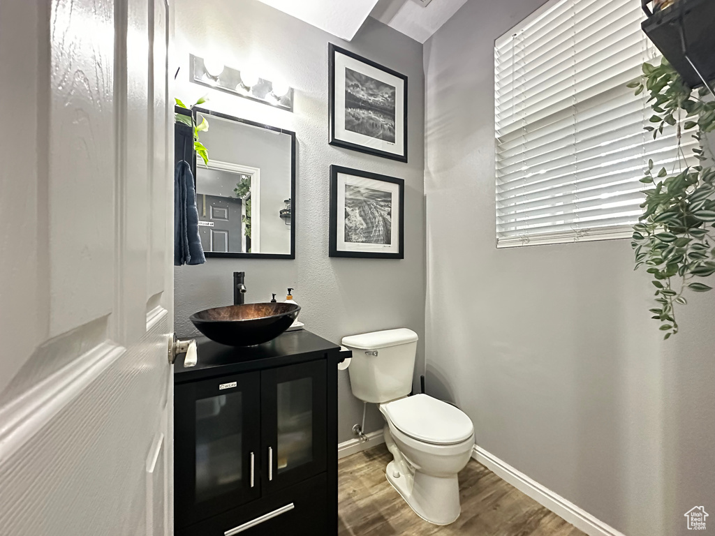 Bathroom featuring vanity, toilet, baseboards, and wood finished floors