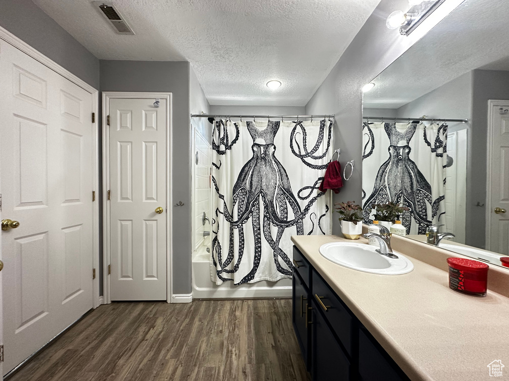 Bathroom featuring a textured ceiling, visible vents, wood finished floors, and vanity