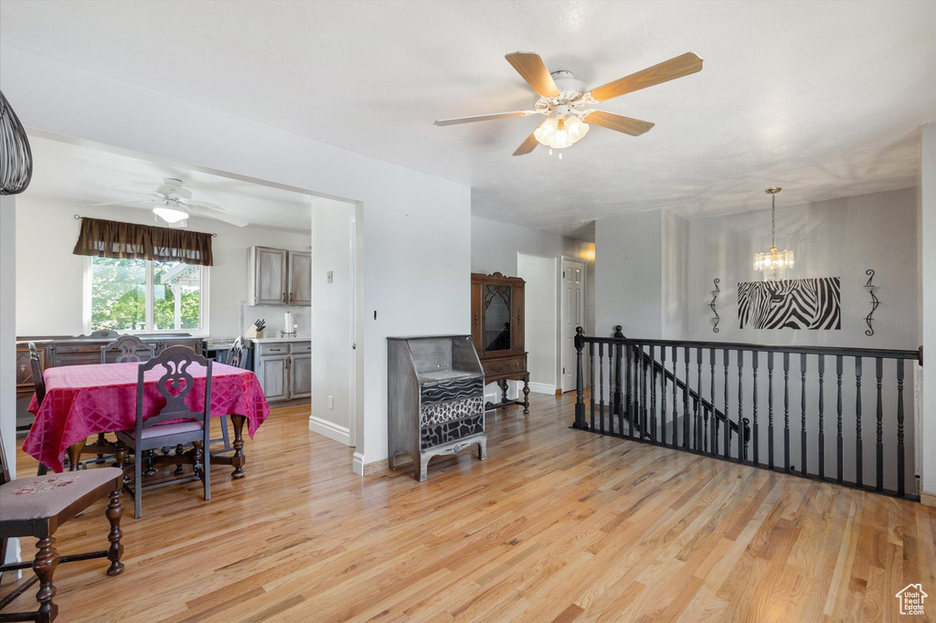 Living room with baseboards, light wood-type flooring, and ceiling fan with notable chandelier