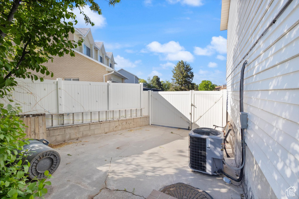 View of patio featuring cooling unit, a fenced backyard, and a gate