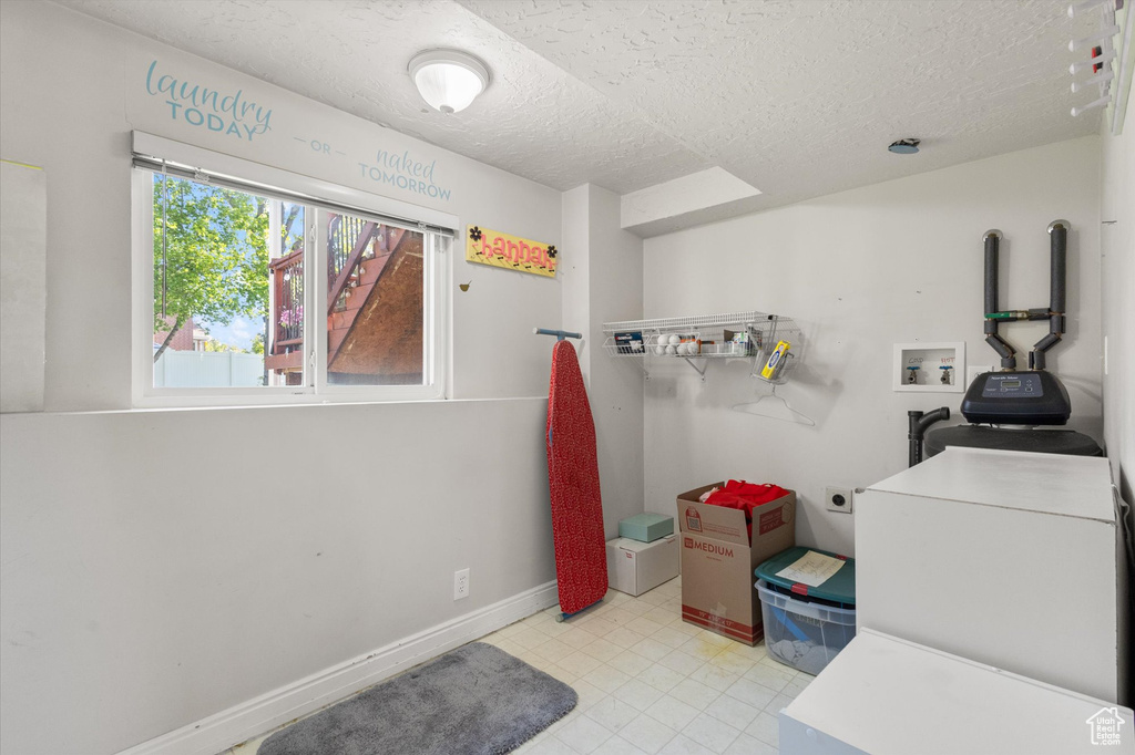 Laundry room featuring light tile patterned floors, electric dryer hookup, laundry area, washer hookup, and a textured ceiling
