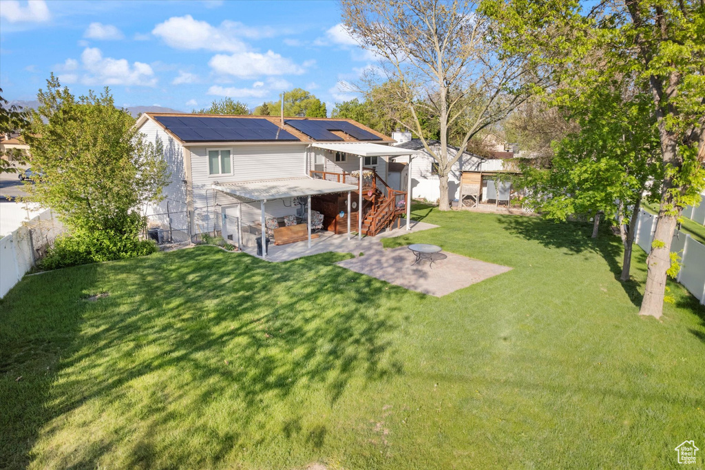 Back of house with a lawn, a patio, stairway, a fenced backyard, and roof mounted solar panels