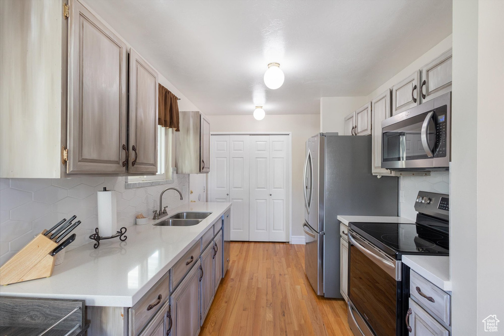 Kitchen with backsplash, light countertops, appliances with stainless steel finishes, and a sink