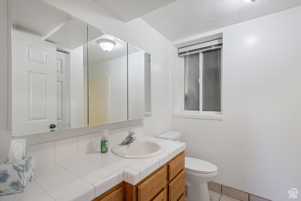 Half bathroom featuring vanity, toilet, and tile patterned flooring