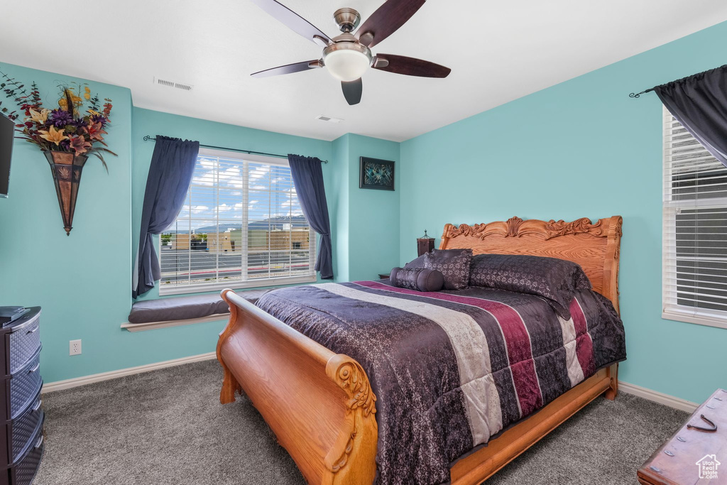 Carpeted bedroom with baseboards, a ceiling fan, and visible vents