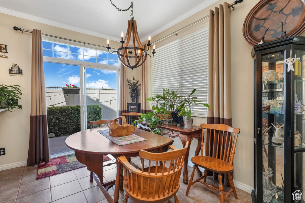 Dining area with a chandelier, light tile patterned flooring, crown molding, and baseboards