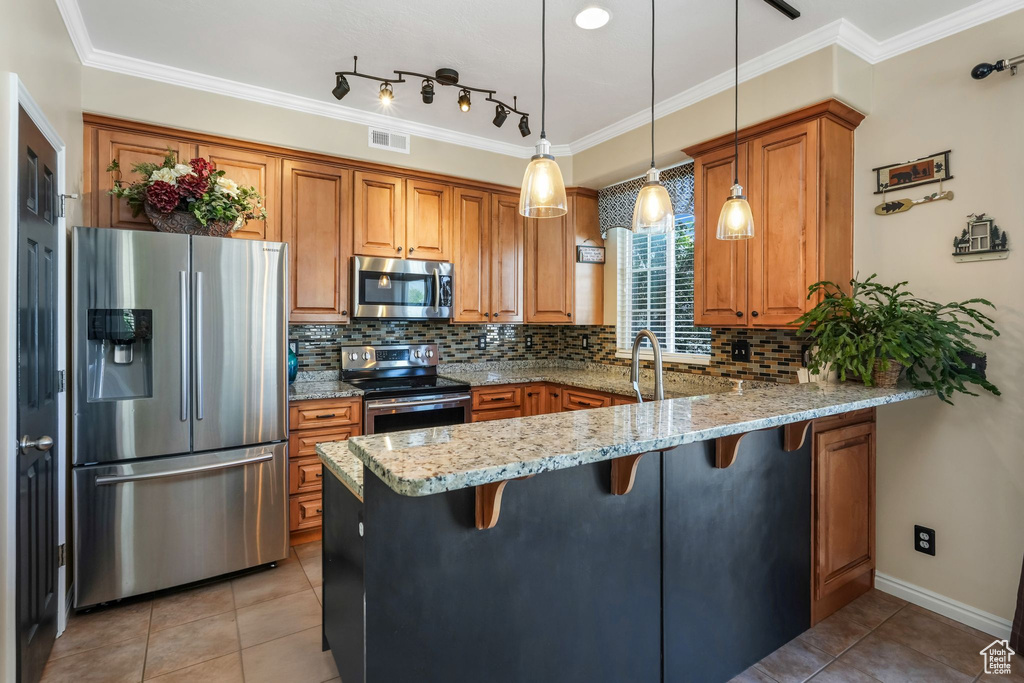 Kitchen with a peninsula, stainless steel appliances, brown cabinetry, and visible vents