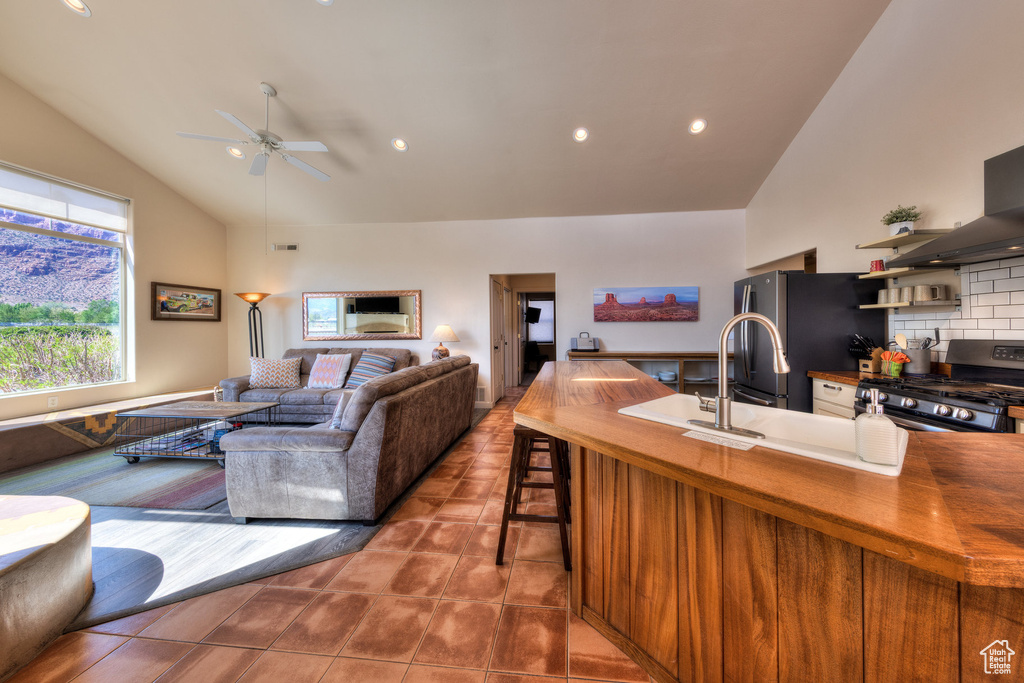 Kitchen with butcher block countertops, ceiling fan, high vaulted ceiling, tasteful backsplash, and appliances with stainless steel finishes