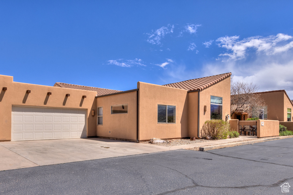 View of front facade featuring a tiled roof, stucco siding, driveway, and a garage