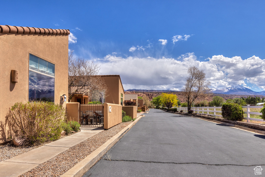View of road featuring a gate, curbs, and a mountain view