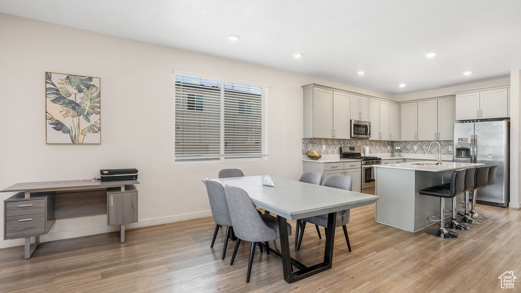 Kitchen with baseboards, appliances with stainless steel finishes, a sink, and light wood-type flooring