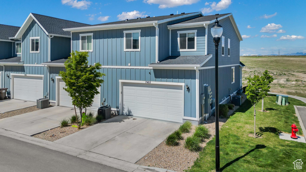 Townhome / multi-family property with concrete driveway, an attached garage, central AC unit, and a front yard