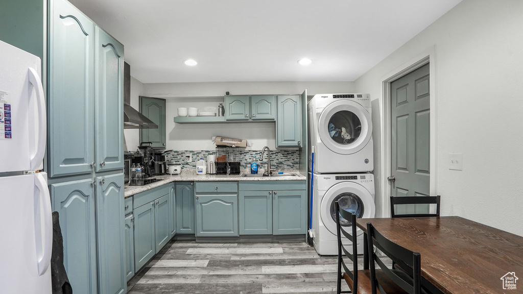 Laundry room with laundry area, recessed lighting, a sink, light wood-style flooring, and stacked washer / drying machine