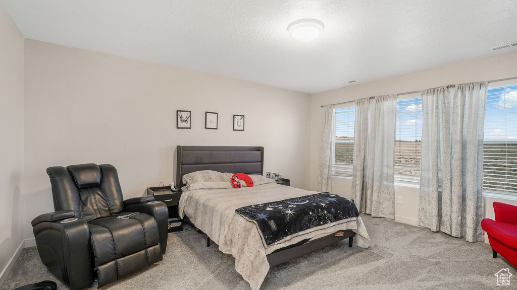 Bedroom featuring baseboards, light carpet, and visible vents