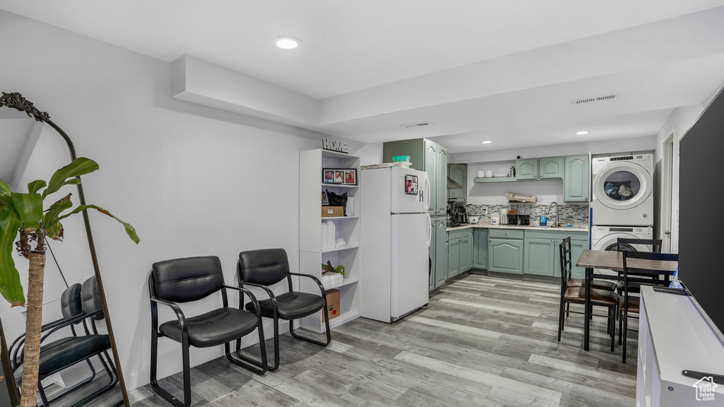 Kitchen with stacked washer and clothes dryer, open shelves, freestanding refrigerator, light wood-style floors, and green cabinets