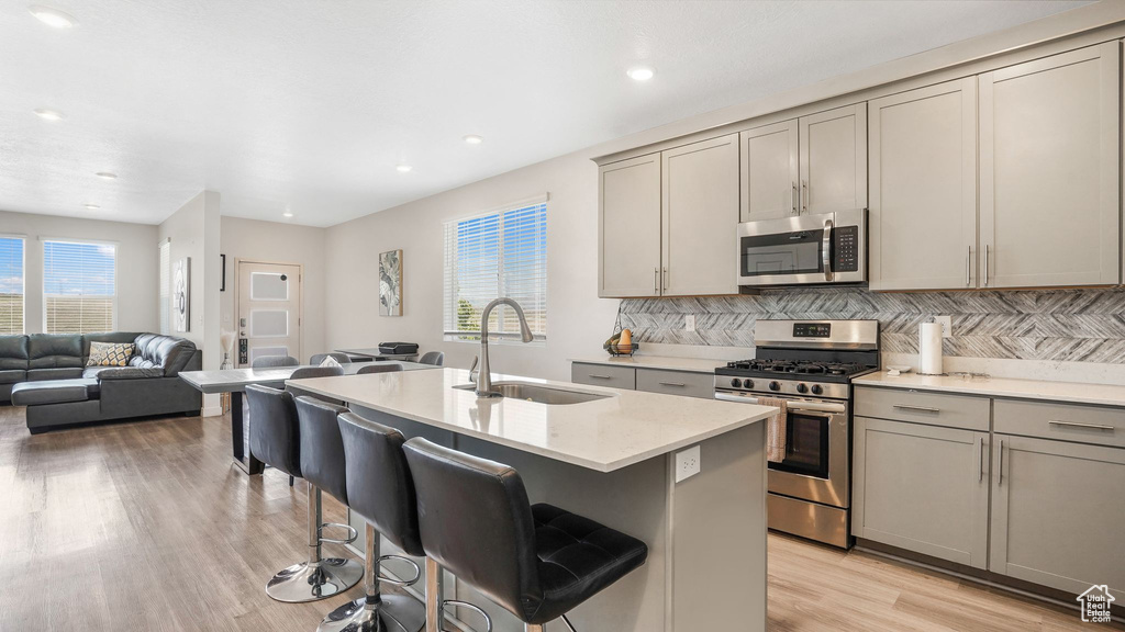 Kitchen with a sink, open floor plan, gray cabinetry, and stainless steel appliances