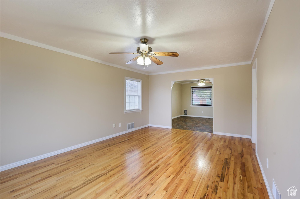 Empty room featuring baseboards, ornamental molding, ceiling fan, and wood finished floors