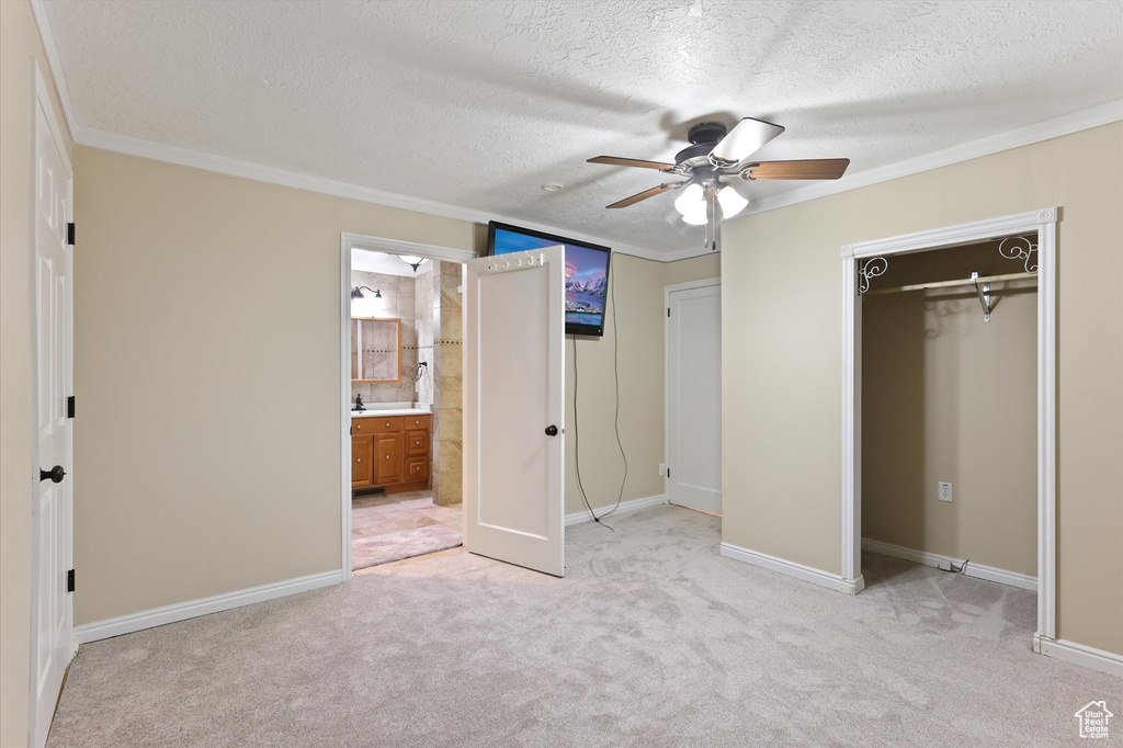 Unfurnished bedroom with a textured ceiling, ornamental molding, and light colored carpet