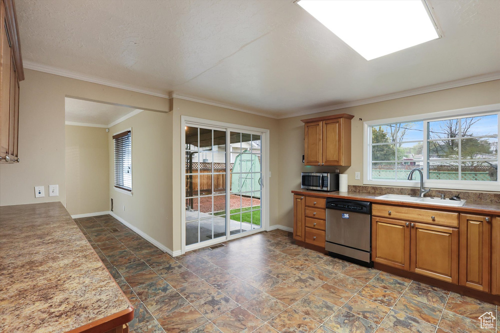Kitchen featuring a healthy amount of sunlight, stainless steel appliances, a sink, and brown cabinets