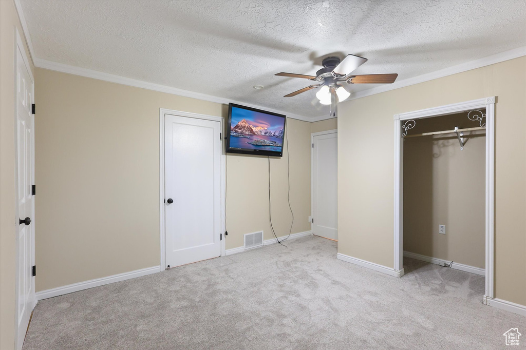 Unfurnished bedroom with carpet, a textured ceiling, visible vents, and crown molding