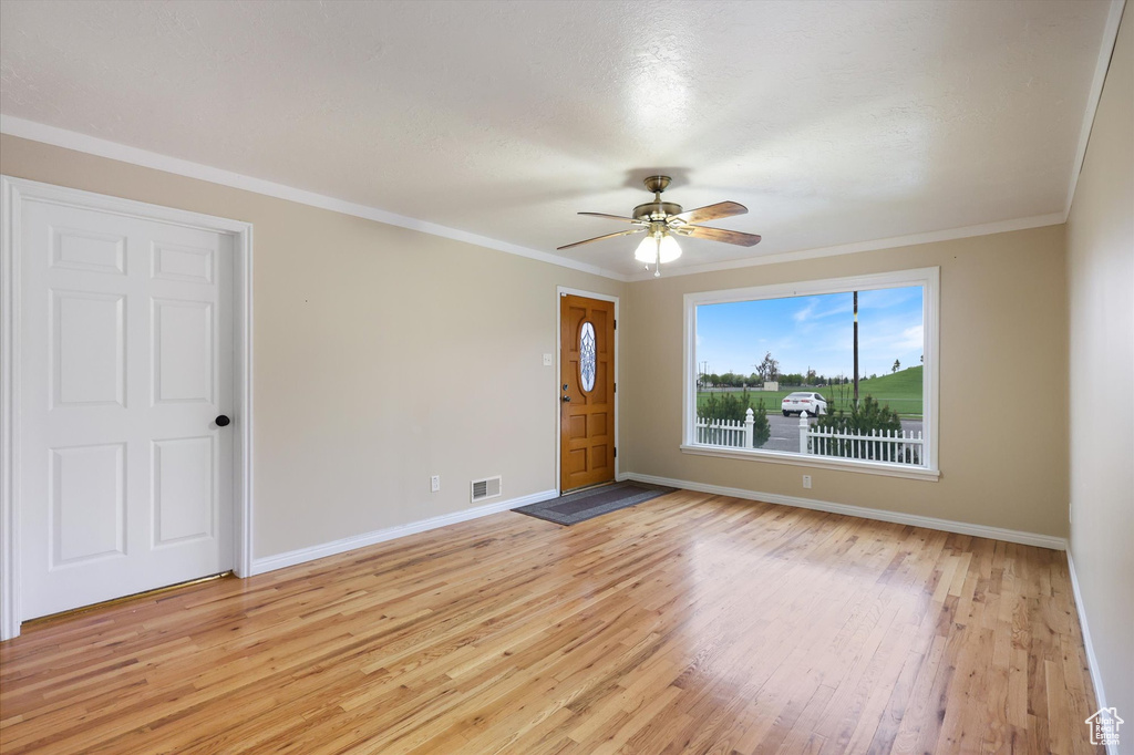 Interior space with light wood finished floors, baseboards, a ceiling fan, and visible vents