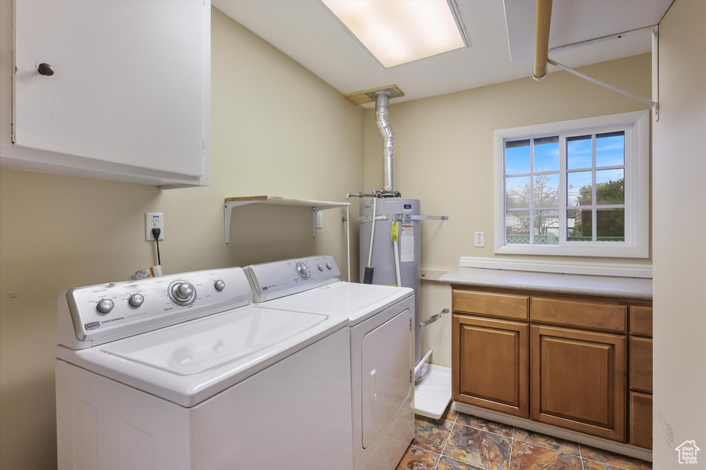 Laundry area featuring stone finish flooring, independent washer and dryer, and cabinet space