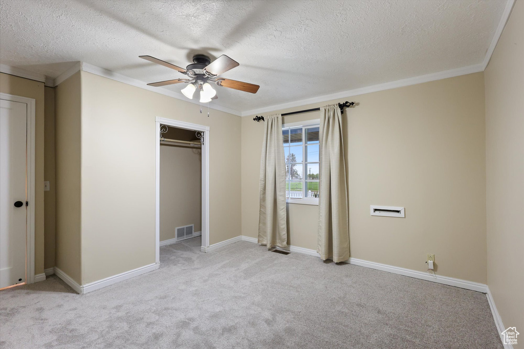 Unfurnished bedroom featuring crown molding, a textured ceiling, carpet floors, and visible vents