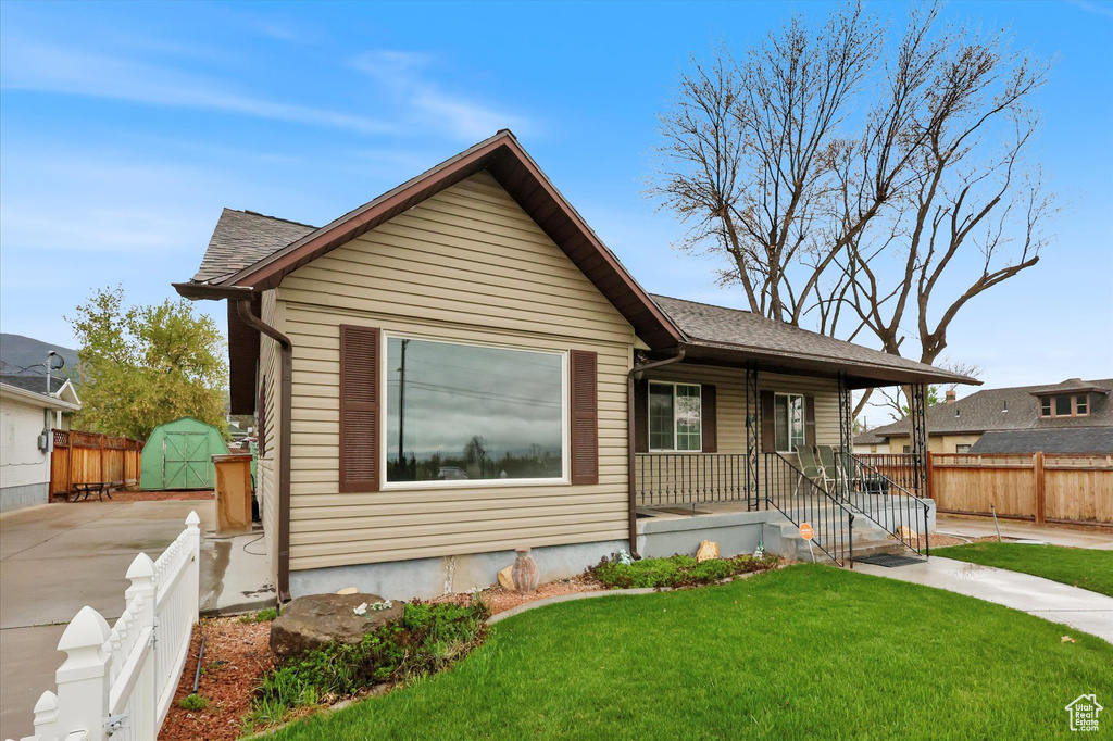 Bungalow-style house with covered porch, a storage unit, an outbuilding, a front yard, and fence private yard