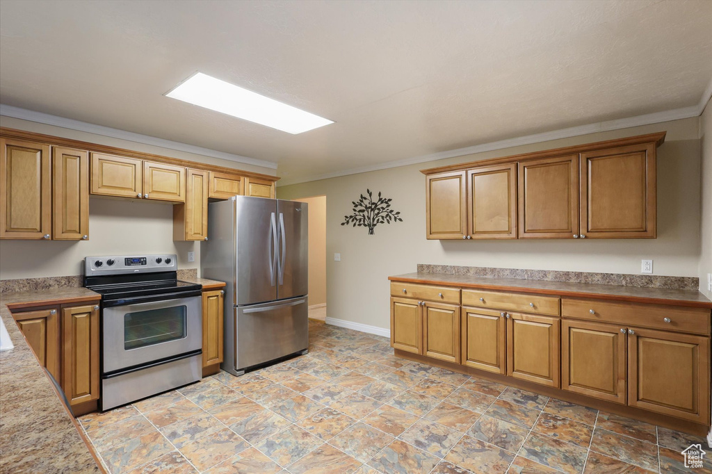 Kitchen with light countertops, appliances with stainless steel finishes, brown cabinetry, and ornamental molding