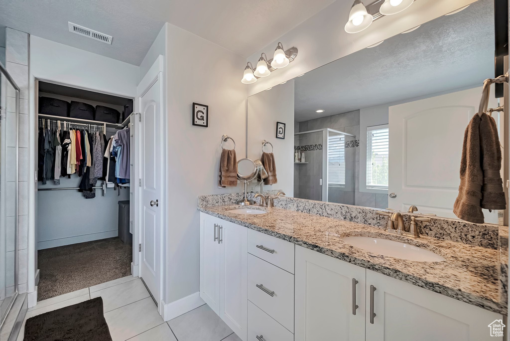 Bathroom with visible vents, a sink, tile patterned floors, and a shower stall