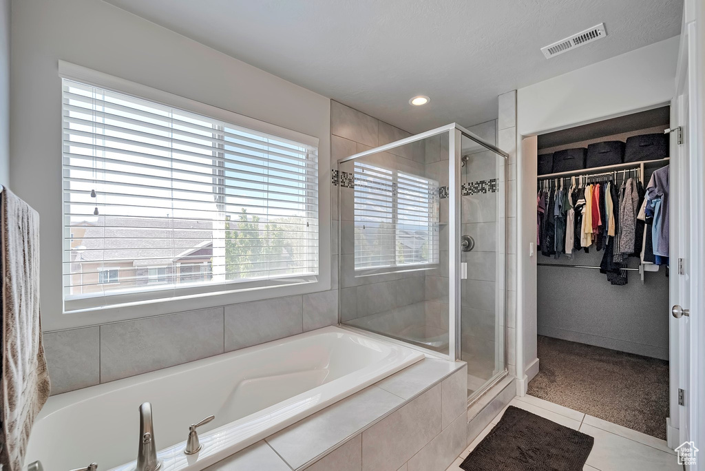 Full bath with tile patterned floors, visible vents, a wealth of natural light, and a stall shower