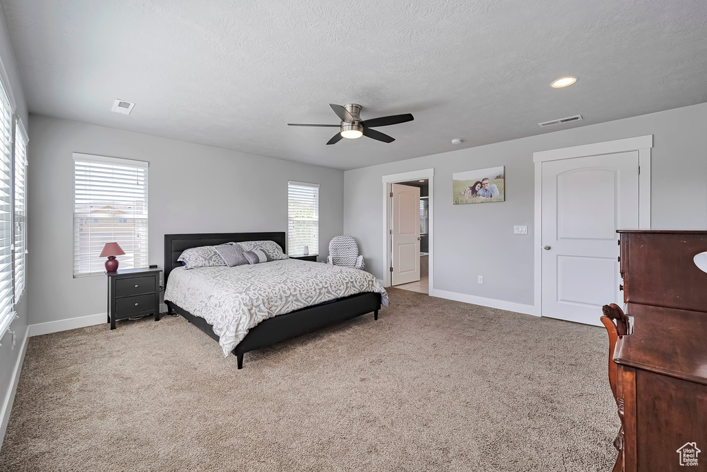 Carpeted bedroom with baseboards, ceiling fan, a textured ceiling, and visible vents