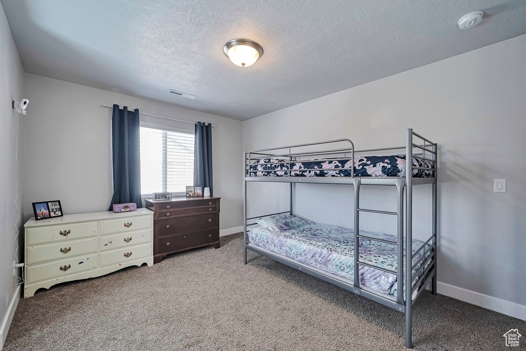 Bedroom with visible vents, carpet flooring, baseboards, and a textured ceiling