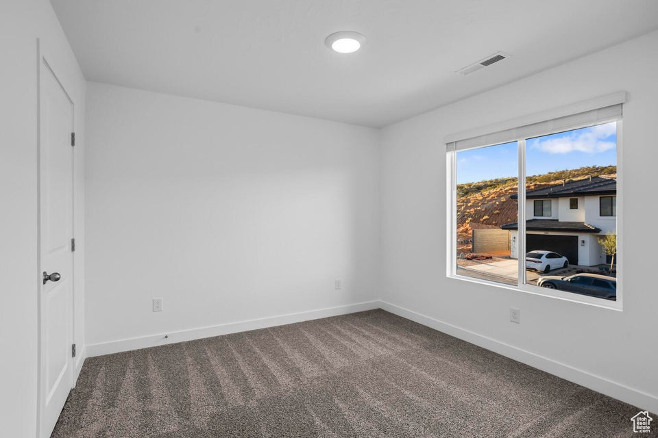 Carpeted empty room featuring baseboards and visible vents
