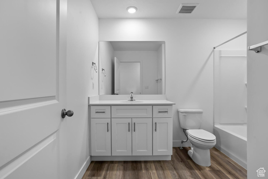 Bathroom featuring toilet, baseboards, visible vents, vanity, and wood finished floors