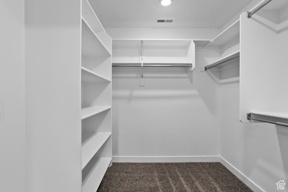 Walk in closet with visible vents and dark carpet