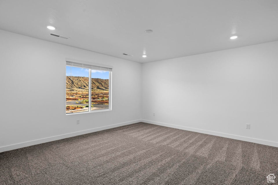 Carpeted empty room with visible vents, baseboards, and recessed lighting