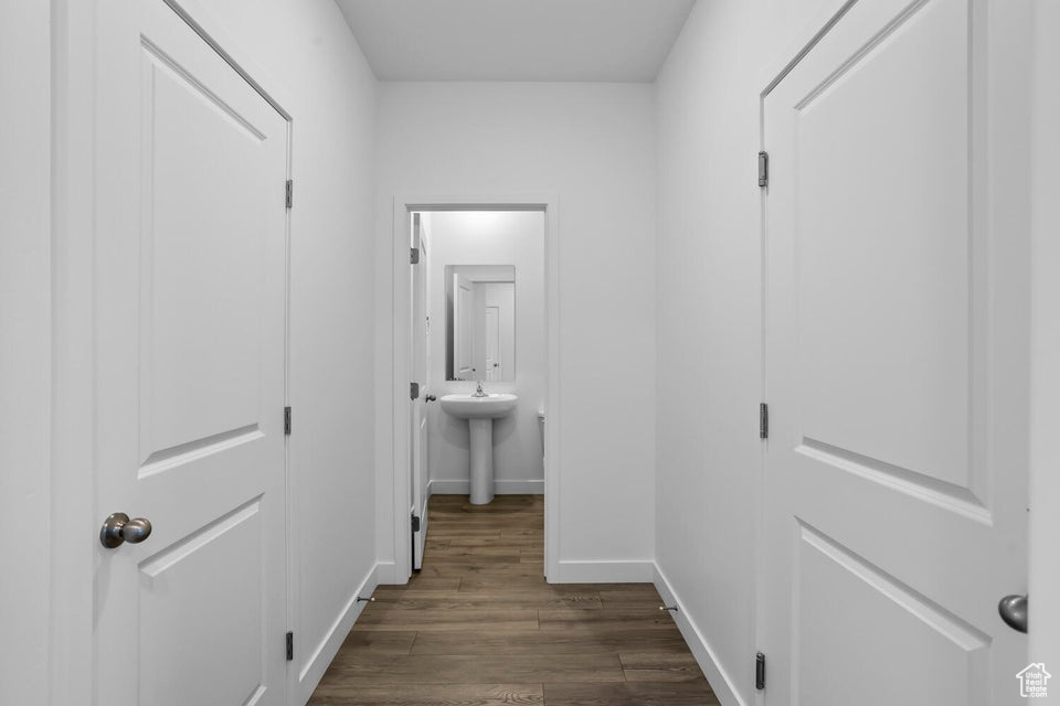 Corridor featuring a sink, baseboards, and dark wood finished floors
