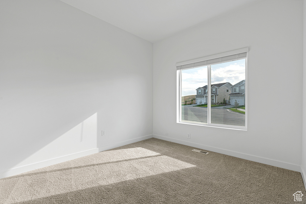Carpeted spare room featuring baseboards and visible vents